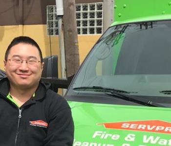 A male employee standing in front of a SERVPRO truck. 